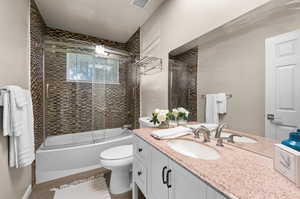 Full bathroom with bath / shower combo with glass door, vanity, toilet, and hardwood / wood-style flooring