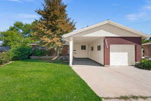 View of front of home with a carport, a garage, and a front yard