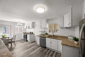 Kitchen featuring sink, decorative light fixtures, a chandelier, white cabinetry, and appliances with stainless steel finishes