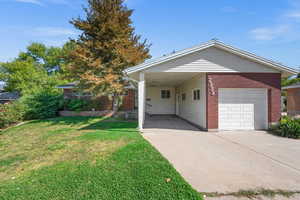 View of front of home featuring a carport, a garage, and a front yard