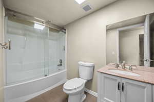 Full bathroom featuring shower / bath combination with glass door, vanity, and toilet