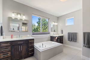 Bathroom featuring tiled tub, vanity, and tile patterned flooring