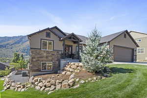 View of front of home with a mountain view, a front lawn, central AC unit, and a garage