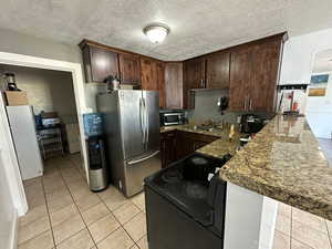 Kitchen featuring light stone countertops, stainless steel appliances, kitchen peninsula, and a textured ceiling