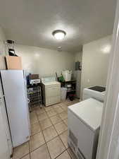 Laundry room with a textured ceiling and light tile patterned floors