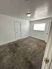 Carpeted spare room with a textured ceiling