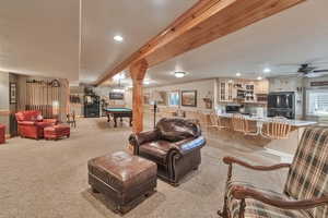 Carpeted living room with beam ceiling, pool table, and crown molding