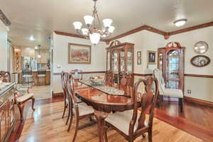 Dining space with light wood-type flooring, a textured ceiling, and a notable chandelier