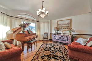 Living room featuring an inviting chandelier, light wood-type flooring, and vaulted ceiling