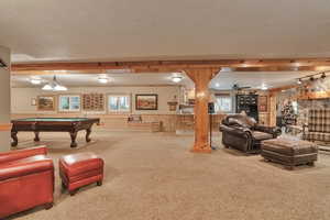 Recreation room featuring a textured ceiling, a fireplace, wooden walls, carpet, and billiards