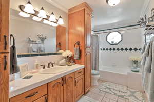 Full bathroom with shower / bathtub combination with curtain, tile patterned floors, ornamental molding, vanity, and toilet