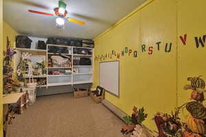 Interior space with ceiling fan, carpet floors, and a textured ceiling