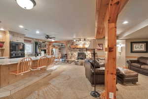 Living room with ceiling fan, light colored carpet, a fireplace, and a textured ceiling