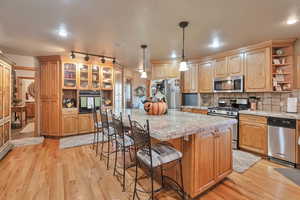 Kitchen featuring a kitchen island, stainless steel appliances, hanging light fixtures, and light hardwood / wood-style flooring