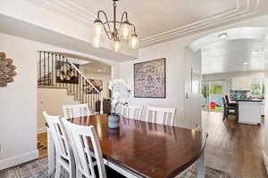 Dining room with a textured ceiling, a raised ceiling, dark hardwood / wood-style floors, and a notable chandelier