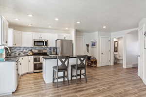 Kitchen featuring light hardwood / wood-style floors, appliances with stainless steel finishes, sink, and a center island