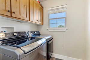 Washroom featuring cabinets, hardwood / wood-style floors, and washer and dryer