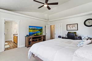 Bedroom featuring ceiling fan, lofted ceiling, connected bathroom, and light carpet