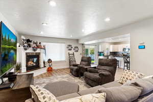 Living room featuring a textured ceiling, light wood-type flooring, and a fireplace