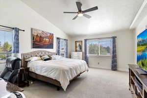 Carpeted bedroom with a textured ceiling, lofted ceiling, and ceiling fan