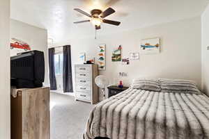 Carpeted bedroom with ceiling fan and a textured ceiling