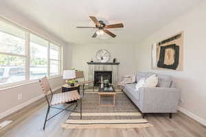 Living room featuring a tile fireplace, hardwood / wood-style floors, and ceiling fan