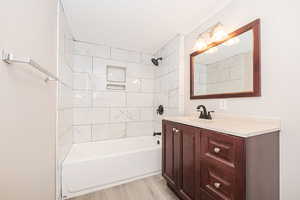 Primary Bathroom featuring vanity, tiled shower / bath combo, and hardwood / wood-style flooring