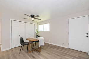 Office with light wood-type flooring and ceiling fan