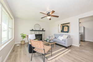 Living room featuring ceiling fan, light wood-type flooring, and a fireplace