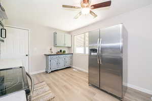 Kitchen with stainless steel fridge, gray cabinetry, range, light wood-type flooring, and ceiling fan