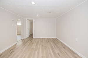 Living room with a textured ceiling and light hardwood / wood-style flooring