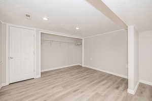 Primary bedroom featuring light hardwood / wood-style flooring, a closet, and a textured ceiling