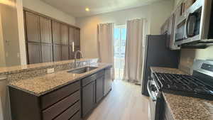 Kitchen featuring dark brown cabinets, stainless steel appliances, light hardwood / wood-style floors, and sink