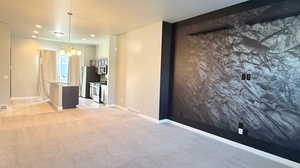 Carpeted Living Dining Combo room featuring an inviting chandelier