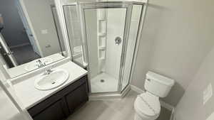 Bathroom featuring wood-type flooring, a shower with door, toilet, and vanity