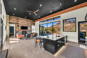 Interior space featuring a large fireplace, sink, concrete floors, a high ceiling, and ceiling fan