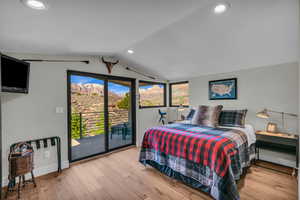 Bedroom featuring lofted ceiling, access to exterior, and light wood-type flooring