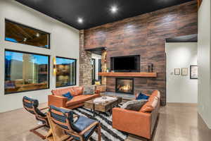 Living room featuring a towering ceiling, concrete flooring, and a tile fireplace