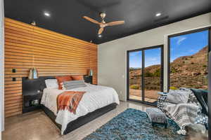 Bedroom featuring a mountain view, access to outside, ceiling fan, and wood walls