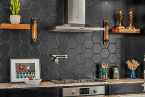 Kitchen featuring stainless steel gas stovetop, oven, decorative backsplash, and wall chimney range hood