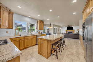 Kitchen with sink, a kitchen island, decorative light fixtures, stainless steel appliances, and a kitchen breakfast bar