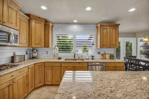 Kitchen featuring light stone countertops, appliances with stainless steel finishes, plenty of natural light, and sink