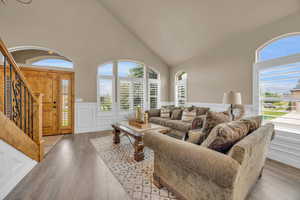 Living room featuring high vaulted ceiling, wood-type flooring, and plenty of natural light