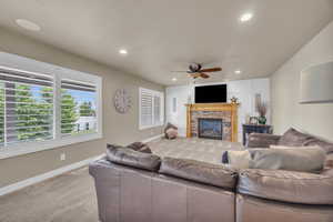 Living room with a fireplace, carpet flooring, and ceiling fan