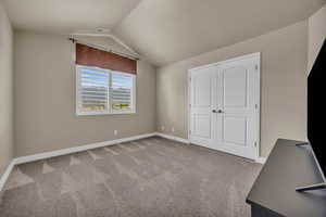 Unfurnished bedroom with carpet floors, lofted ceiling, and a closet