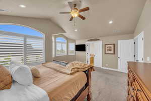 Carpeted bedroom with multiple windows, vaulted ceiling, and ceiling fan