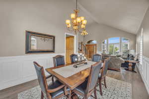 Dining room with an inviting chandelier, light wood-type flooring, and high vaulted ceiling