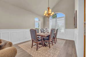 Dining room featuring high vaulted ceiling, light hardwood / wood-style flooring, and a chandelier