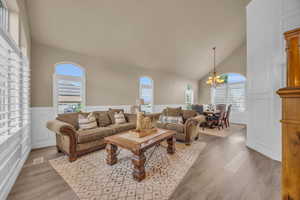 Living room with a chandelier, light hardwood / wood-style floors, and high vaulted ceiling