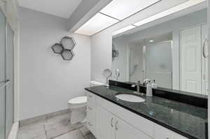 Bathroom featuring vanity, a shower with shower door, toilet, and tile patterned floors